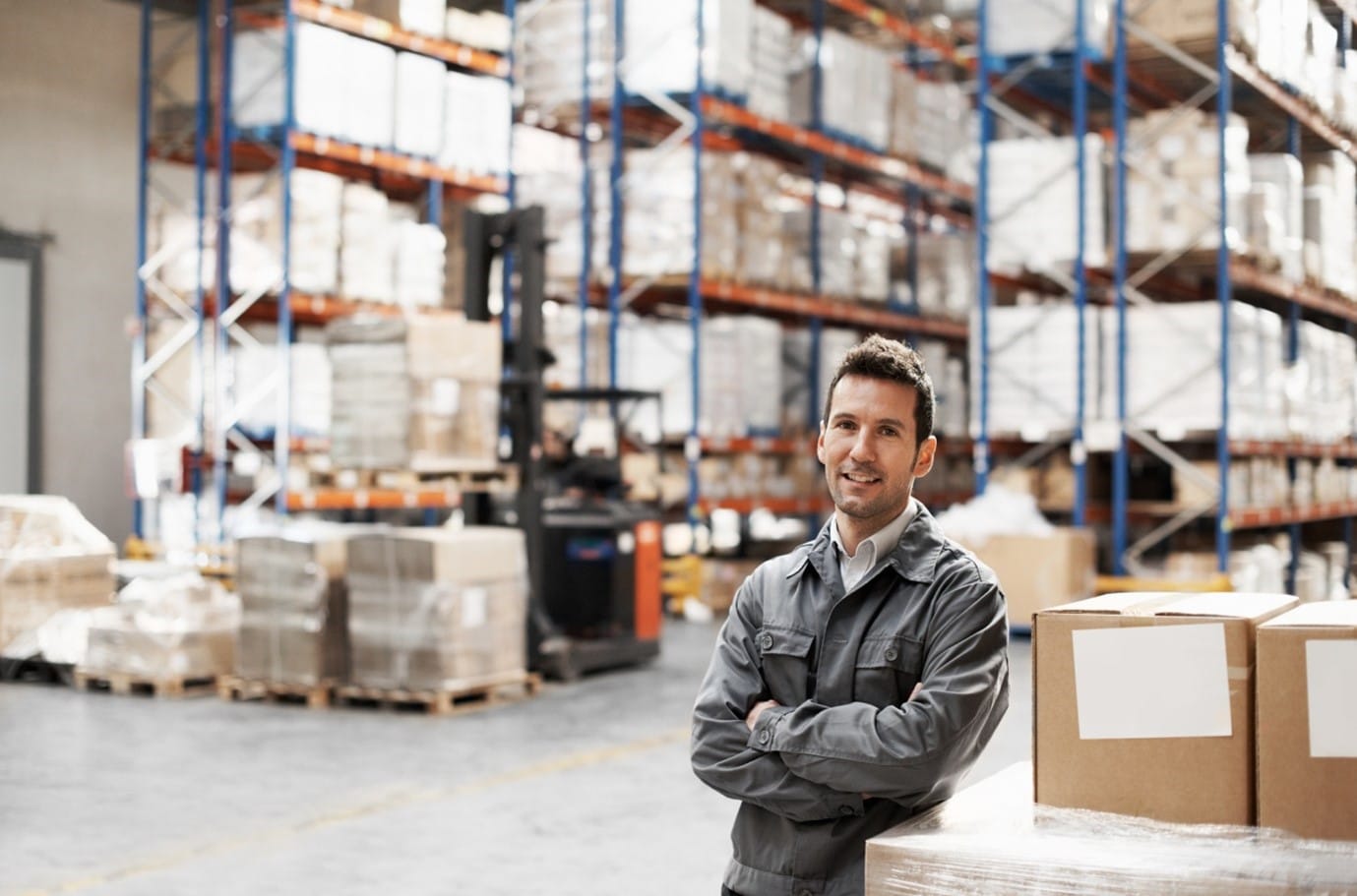 Third-Party Logistics Worker Stands In Front of Fully Stocked Warehouse