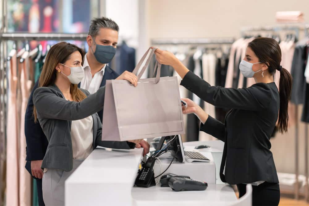 A couple receiving a bag full of purchased items from a merchant