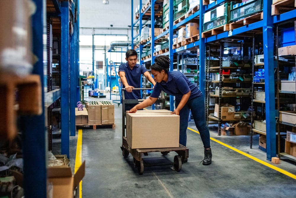 Two workers moving boxes in a warehouse