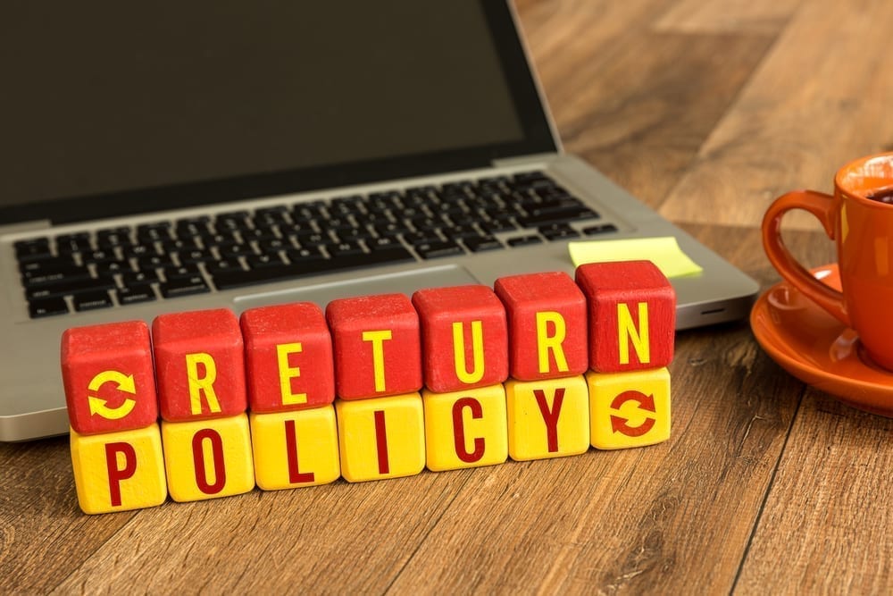 Red and yellow blocks spelling out return policy in front of a laptop.