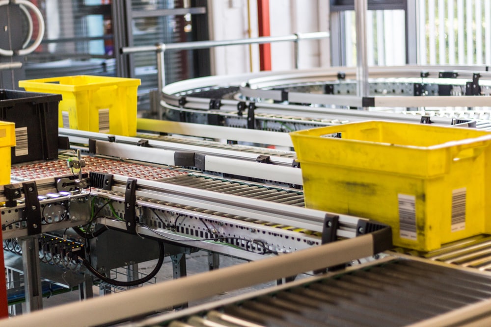 Machines moving yellow bins through a distribution center.