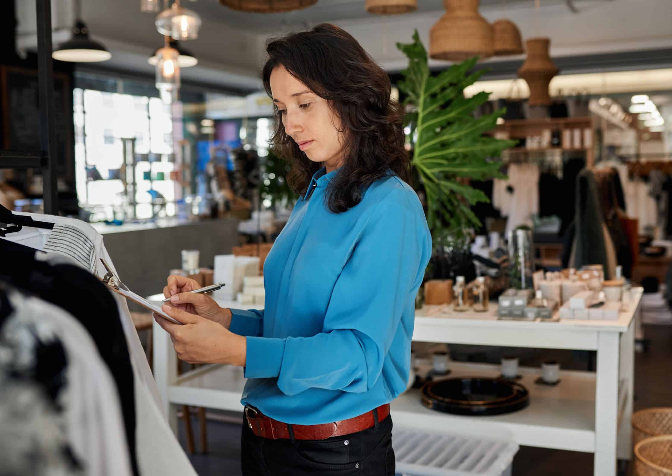 A woman standing in a retail store taking inventory.