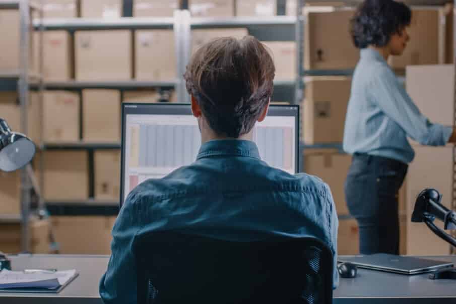 A man working on a spreadsheet on a computer in a warehouse