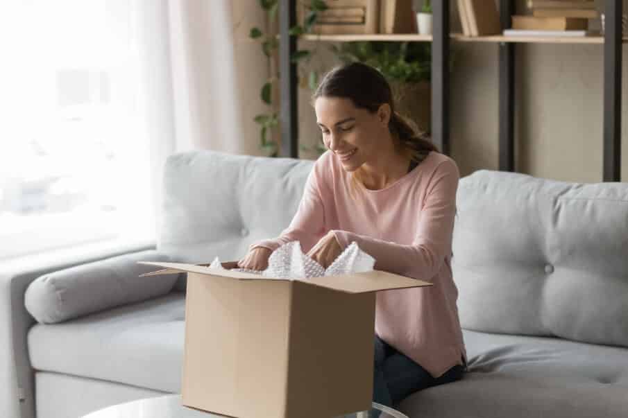 Woman on Couch Unpacks the Content from Her Delivered Package