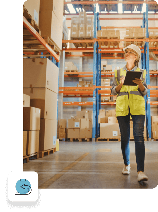 Woman in work gear with tablet walking through warehouse