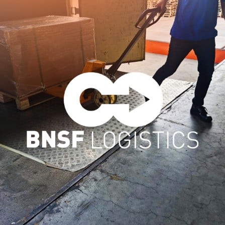 A man pulling a pallet with BNSF Logistics written on the image.