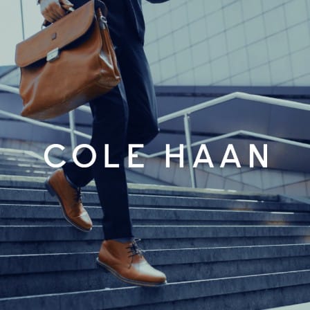 A man wearing Cole Haan boots walking down stairs.