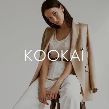 A woman slouched on a stool wearing Kookai.