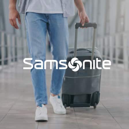A man pulling luggage through an airport with the Samsonite logo
