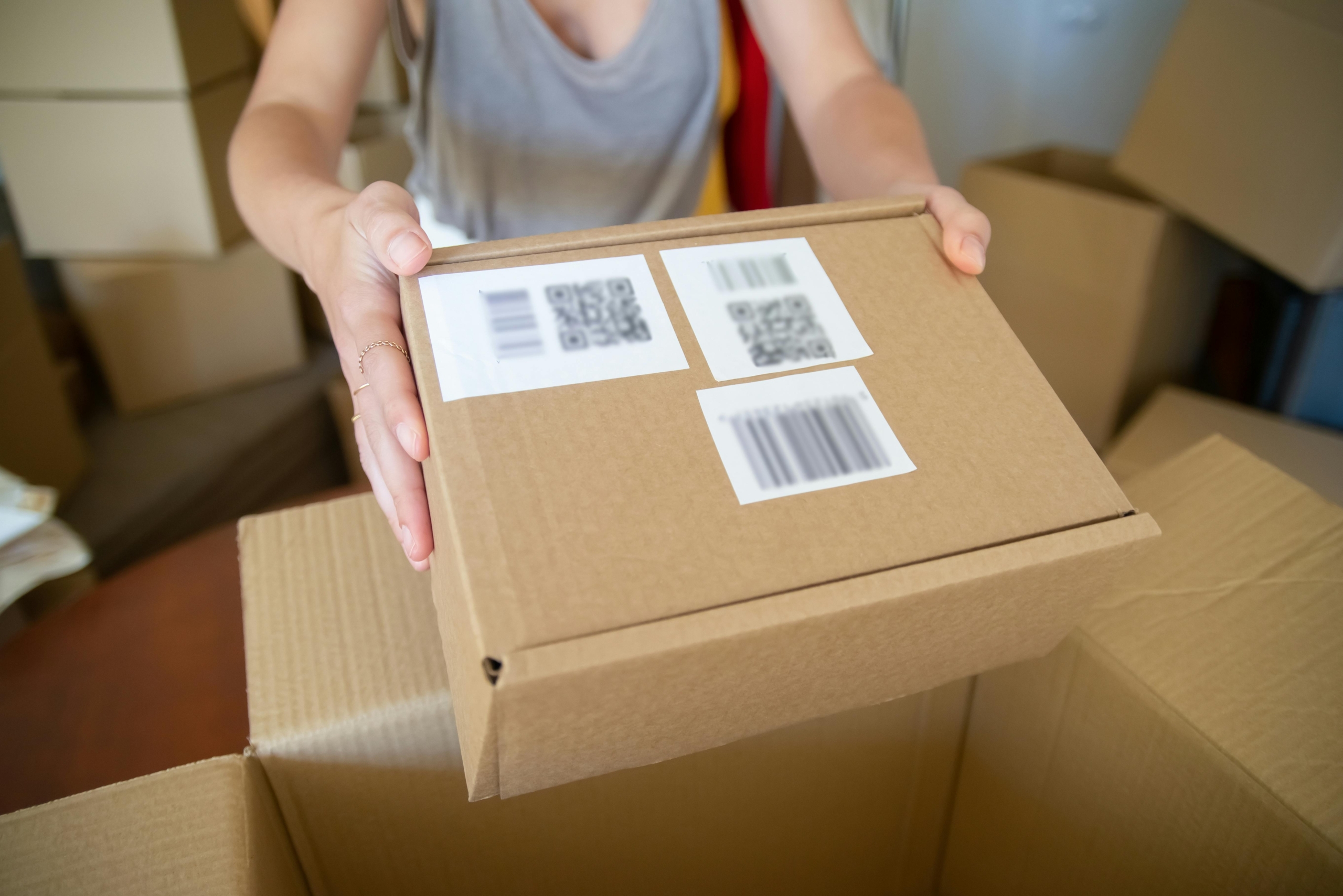 An employee holds a returned product with QR code and return label.