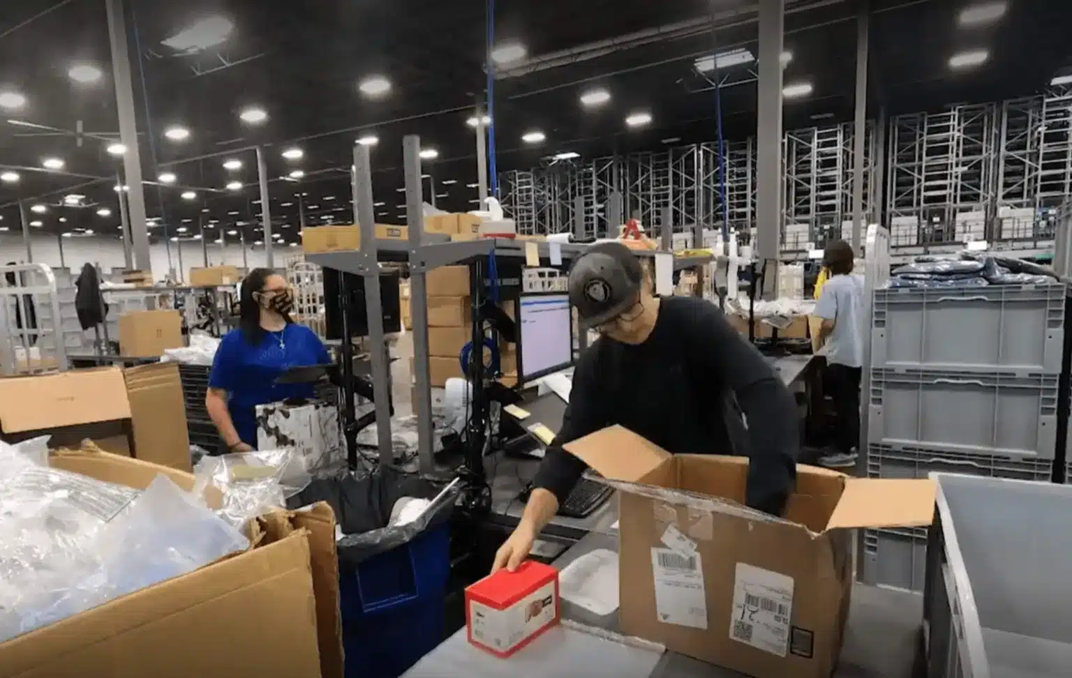 Warehouse associates unpacking and processing returned products at packing stations