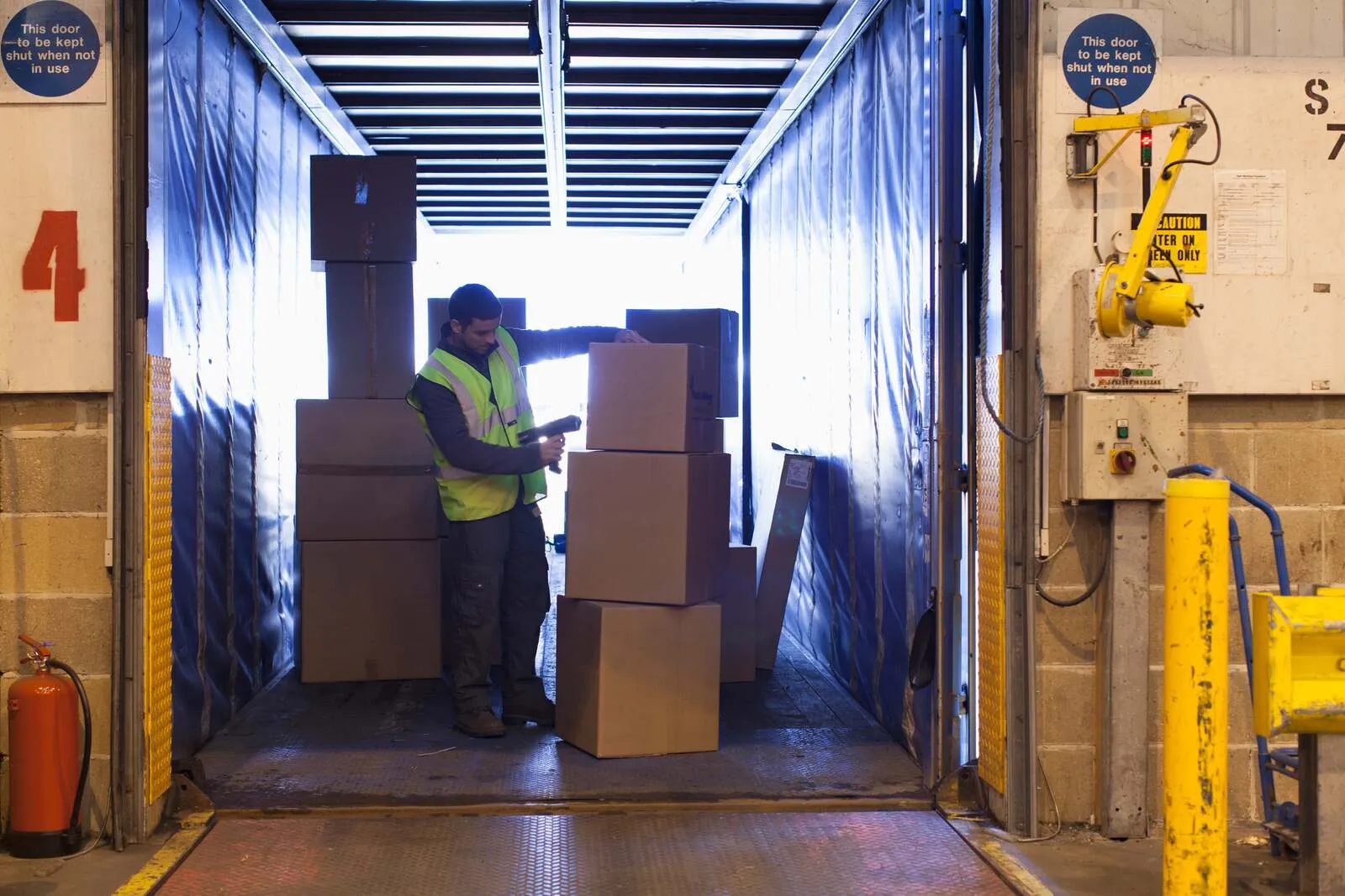 Marketplace and D2C returns management software: returns associate scanning a parcel at a busy ecommerce returns receiving dock