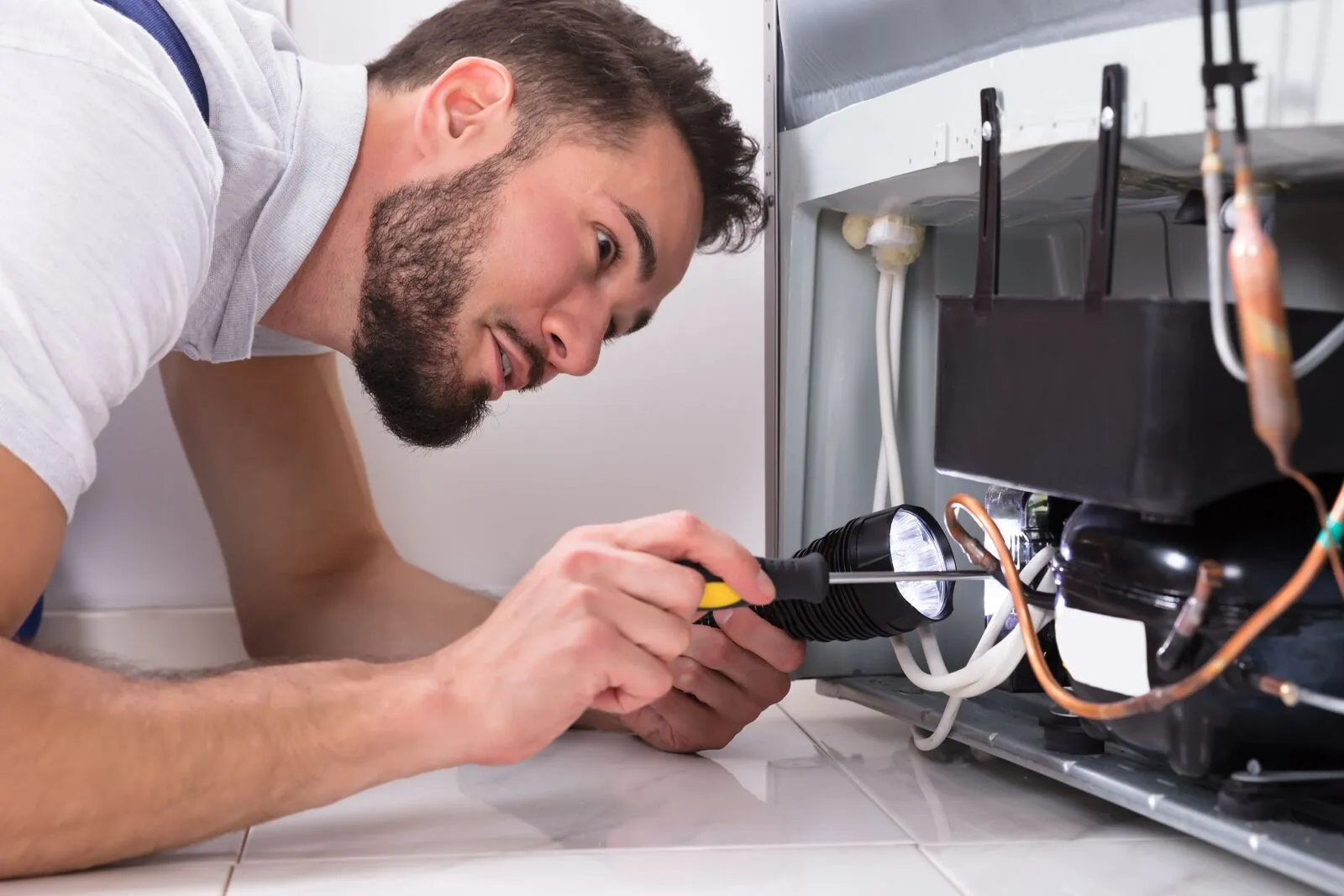 Repair technician testing a returned appliance on a workshop bench before it goes back to the customer