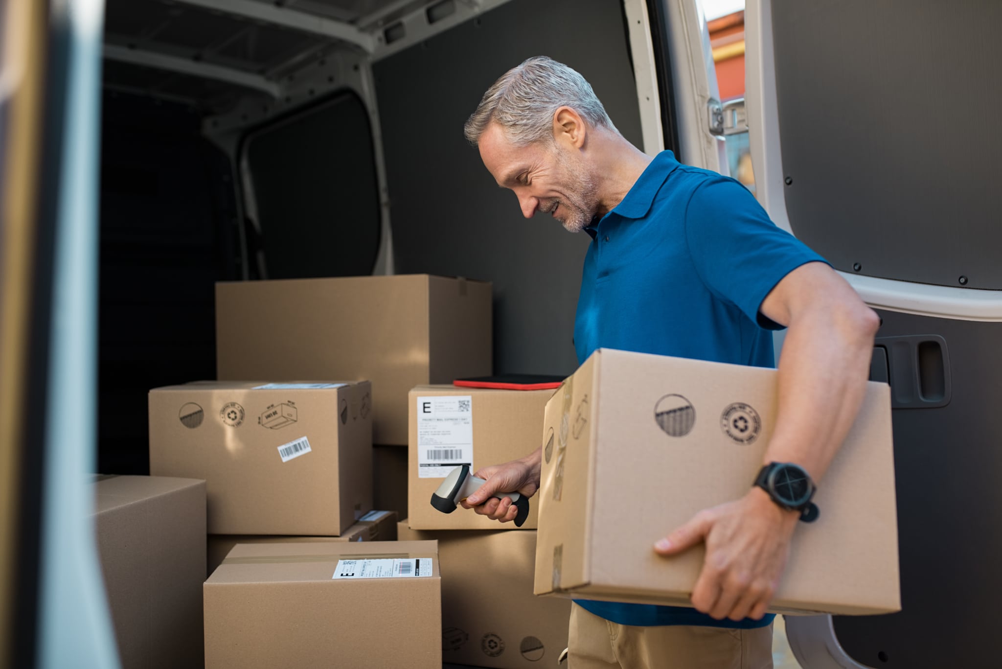 Delivery man scanning package barcodes in a van